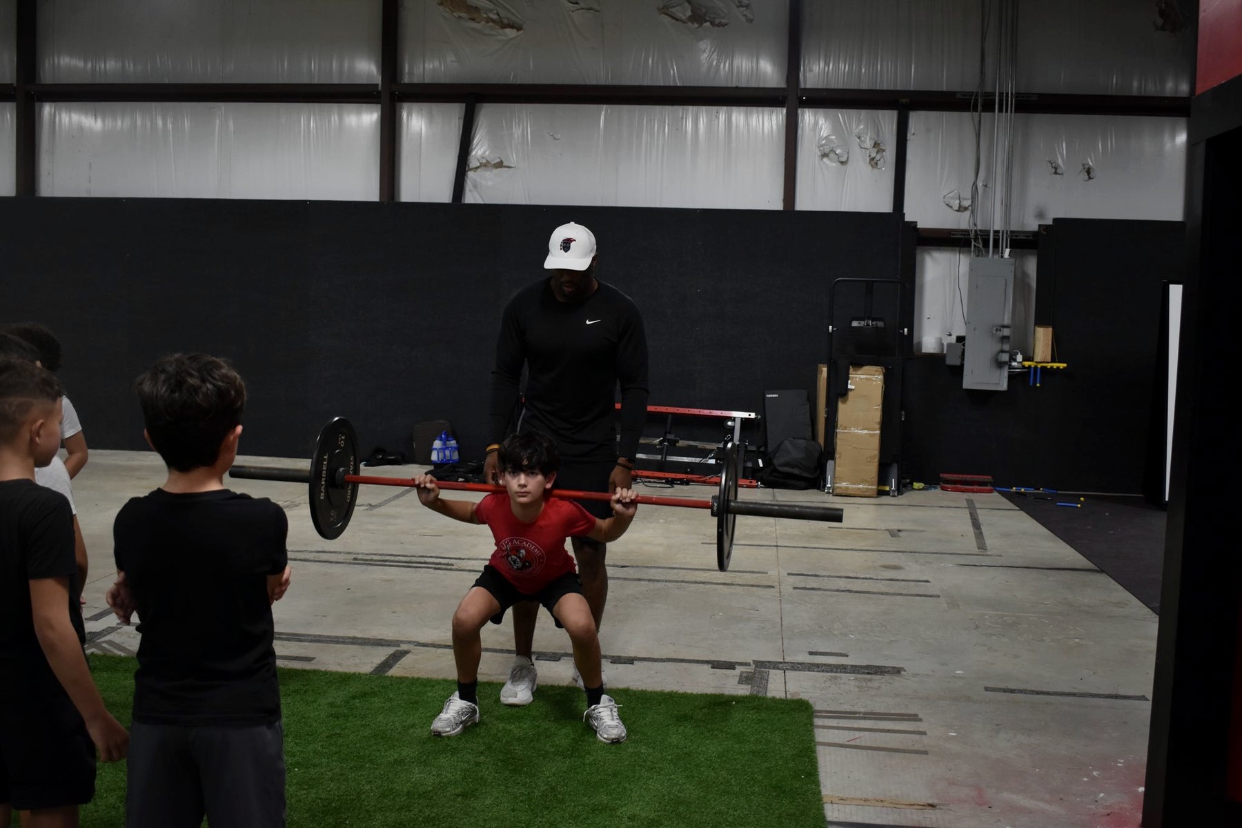 A coach guiding an athlete through a strength lift.